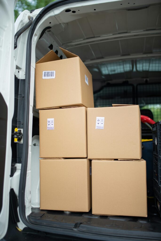 Stacked cardboard boxes inside an open delivery van, ready for shipment.